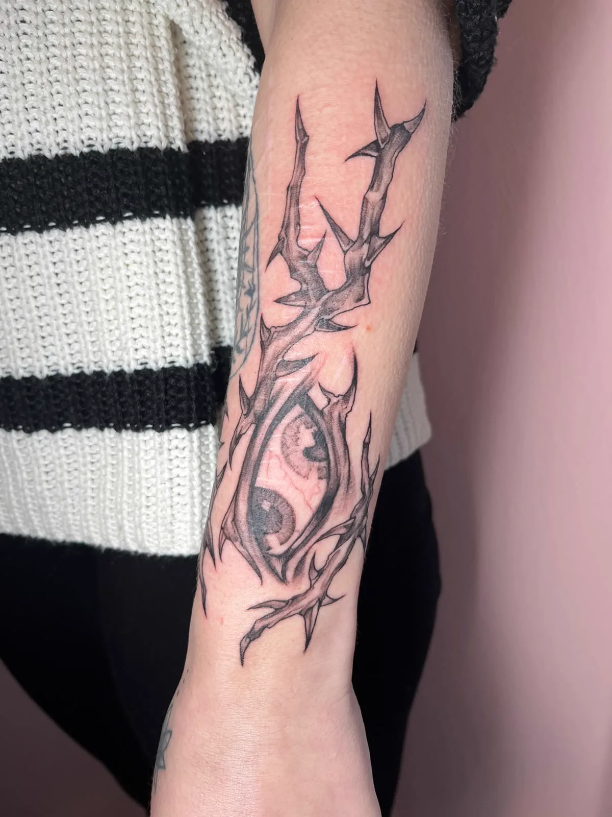 Auge mit Dornenranke am Unterarm