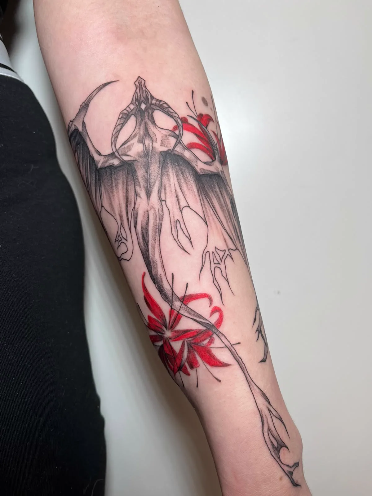 Fledermauswesen mit roten Blüten am Unterarm